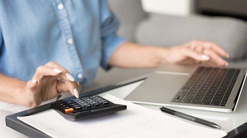Hands Of Mature Female Accountant Typing On Calculator And Laptop Doing Bookkeeping