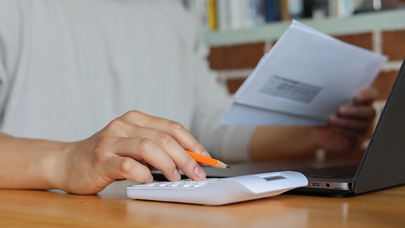 Man Writing On Notebook And Using Calculator Managing Rent Collection